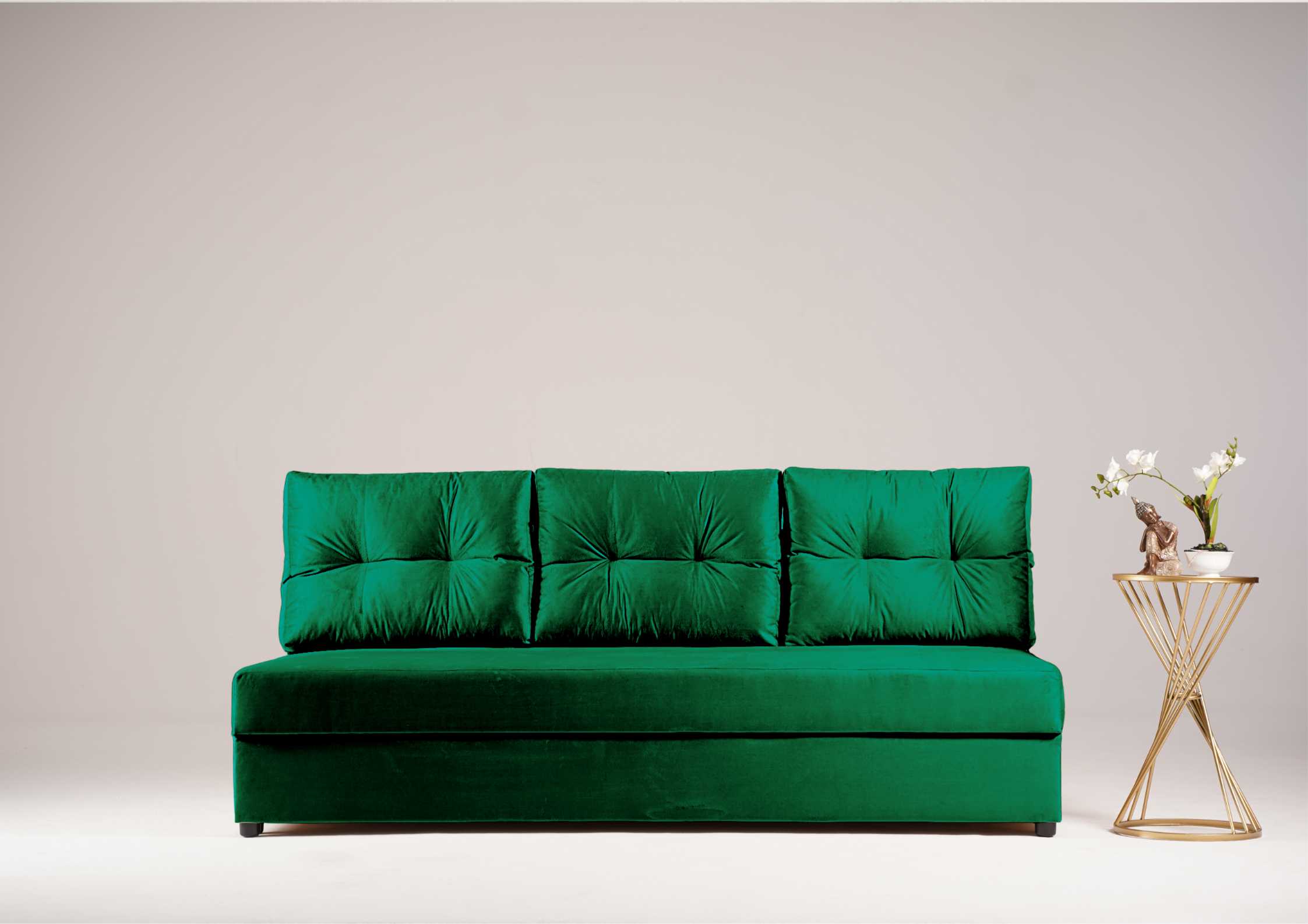 Zielona sofa z pikowanymi poduszkami